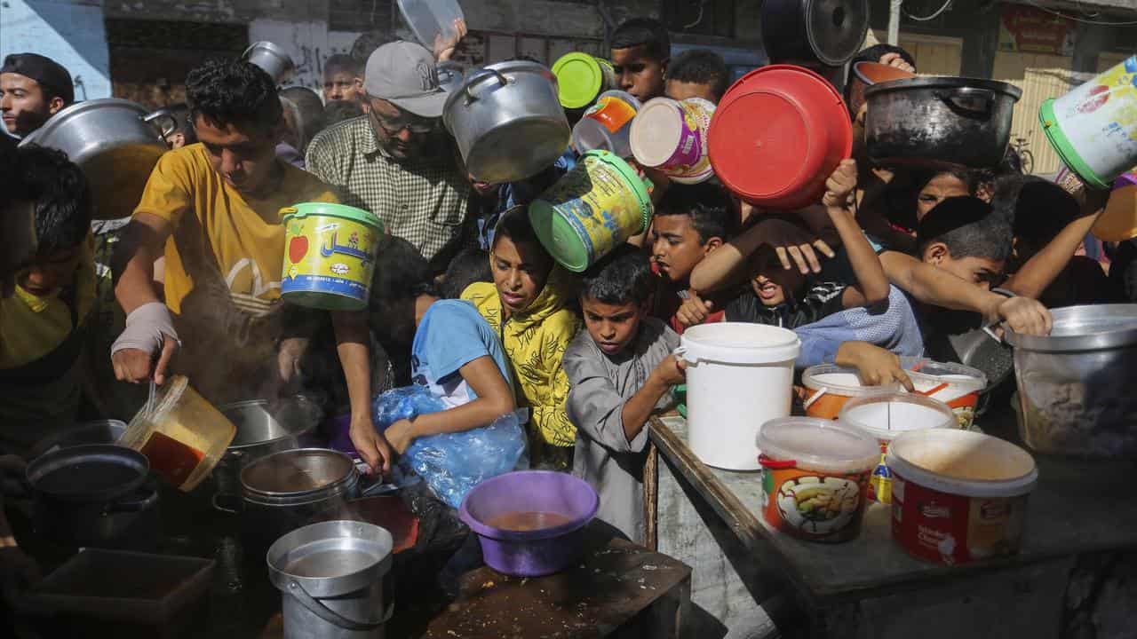 Palestinians wait for food distribution in Rafah