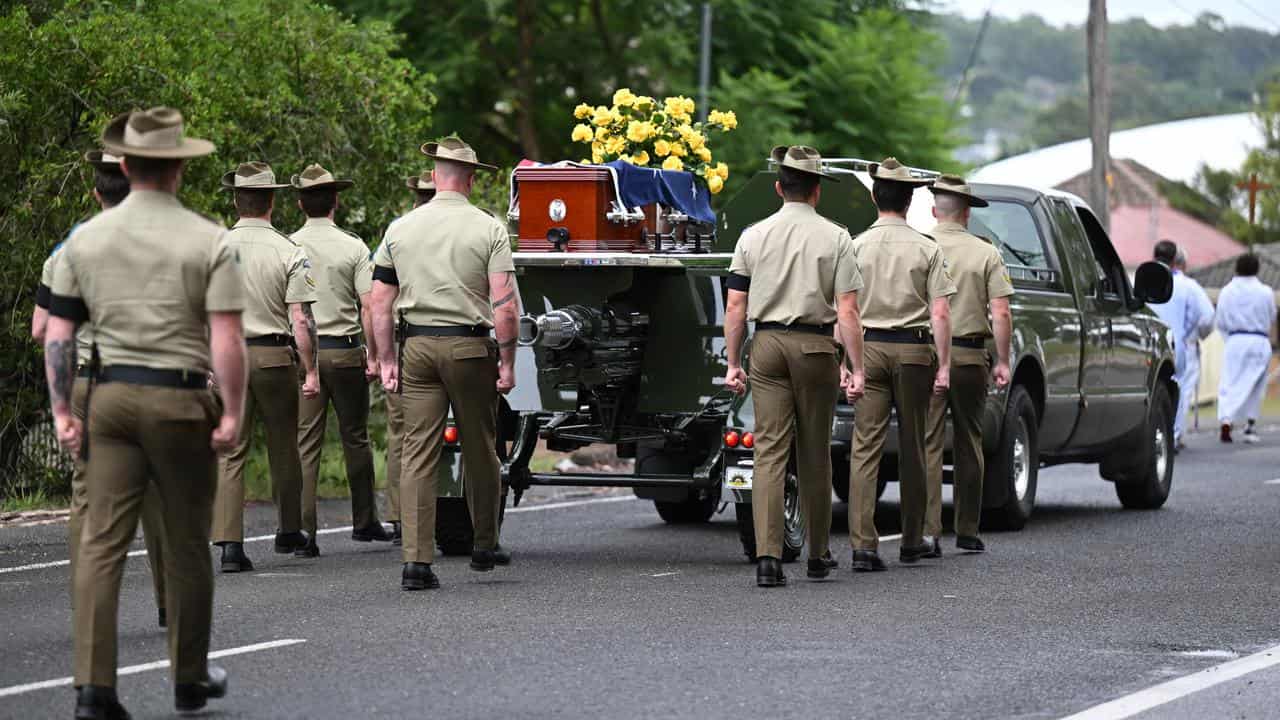 The casket of Jack Fitzgibbon is carried on a gun carriage