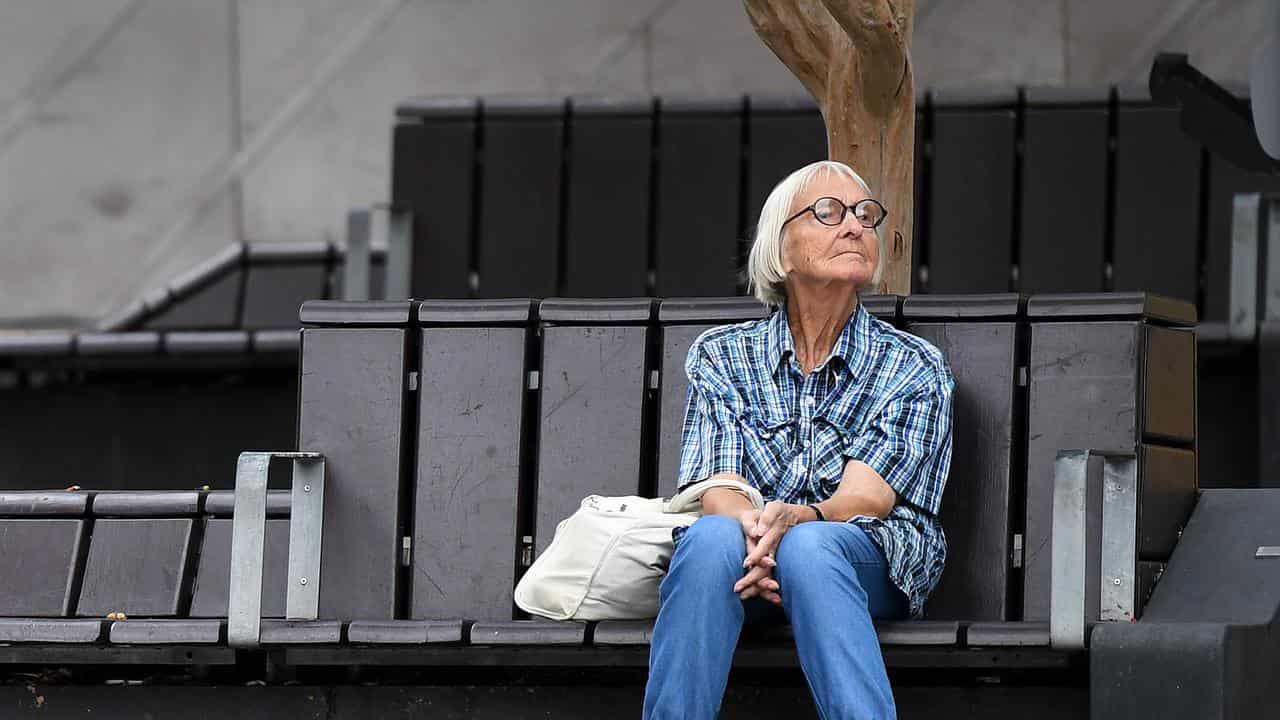 An elderly woman sits on a bench in Brisbane (file)