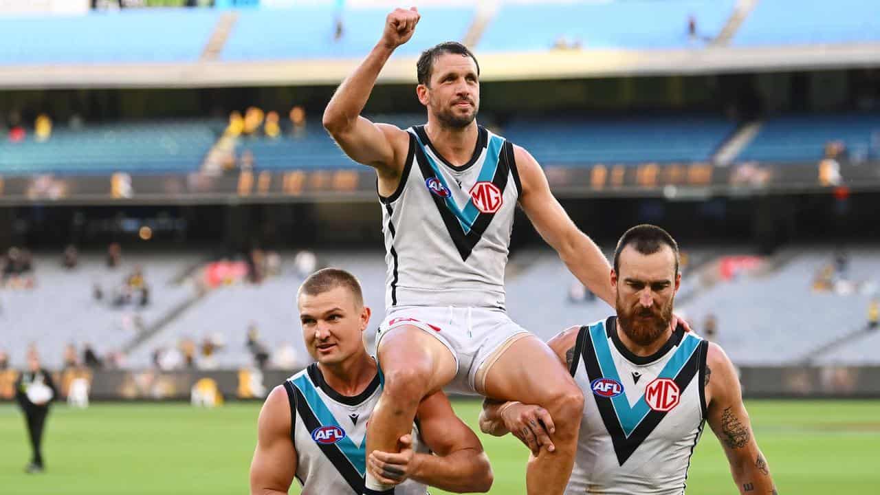 Travis Boak is chaired off the MCG by Ollie Wines and Charlie Dixon.