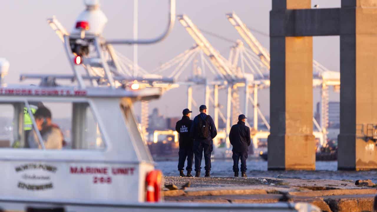 Rescue personnel gather on the shore of the Patapsco River