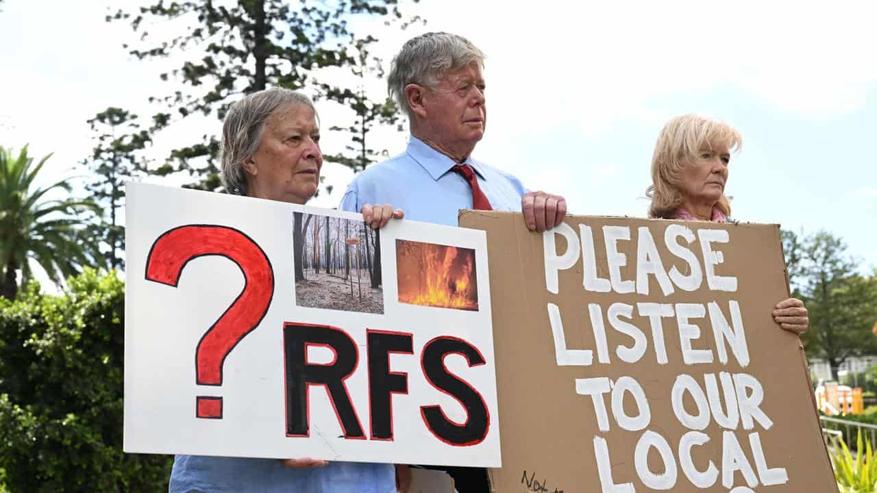 Affected residents hold signs following an inquest into Black Summer