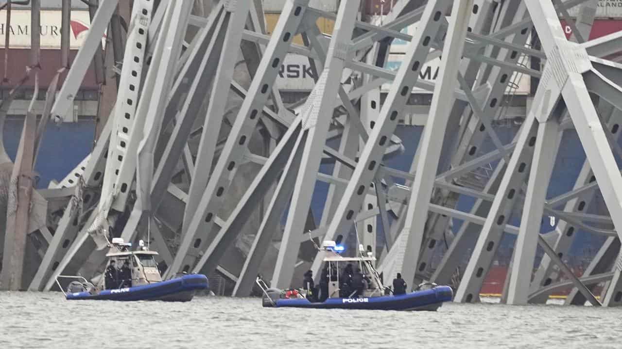 Police boats near a cargo ship under the Francis Scott Key Bridge