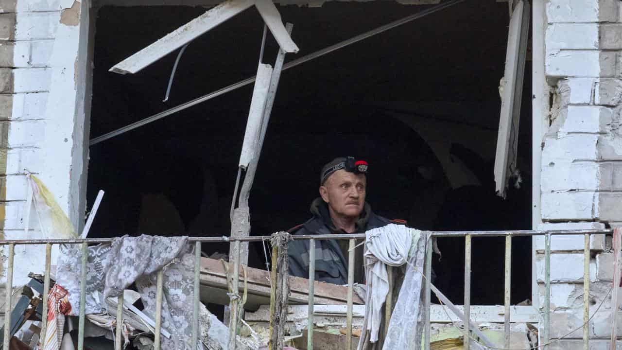 Workers inspect the site of shelling near buildings in Kharkiv