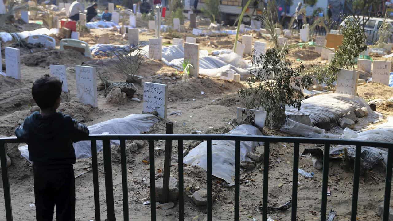 A Palestinian child looks at a makeshift cemetery inside Shifa grounds