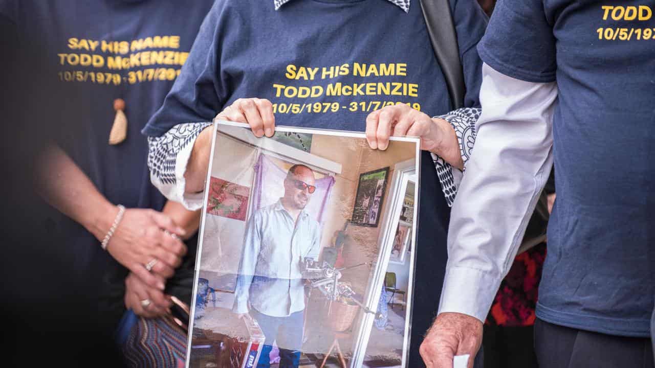 Todd McKenzie's family hold a photo of him outside the Coroner's Court