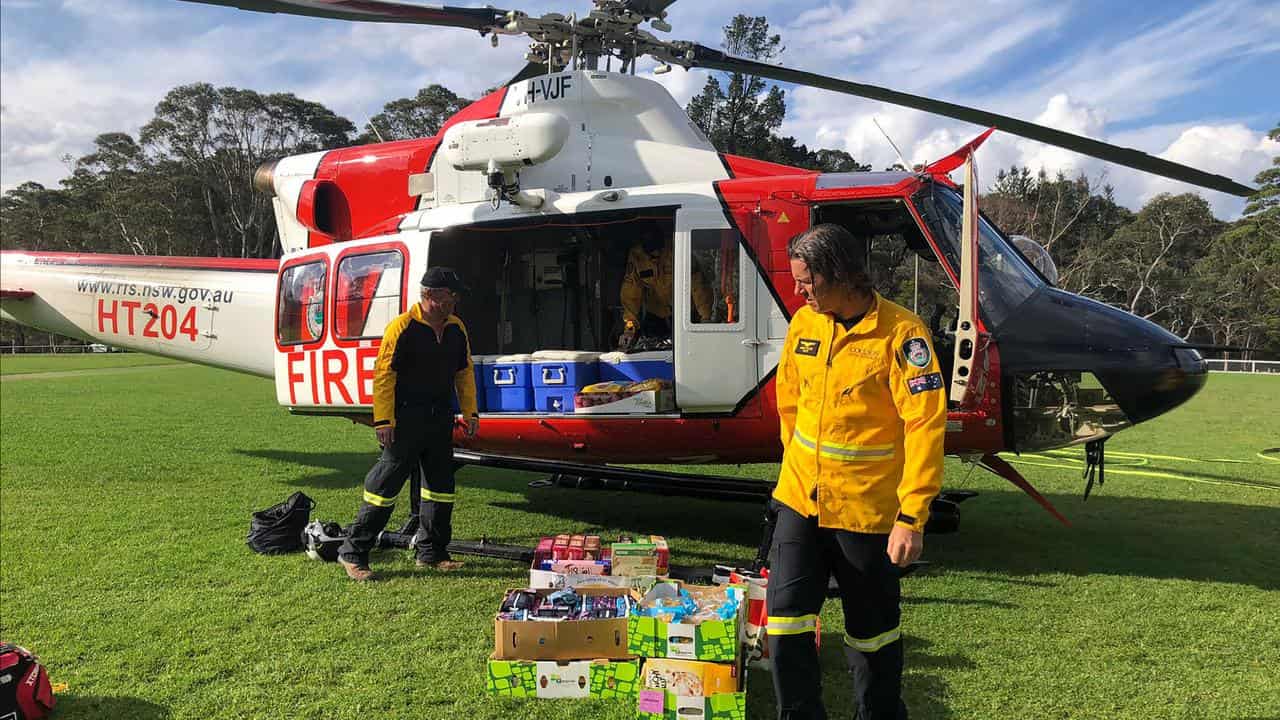 A helicopter with people loading supplies.