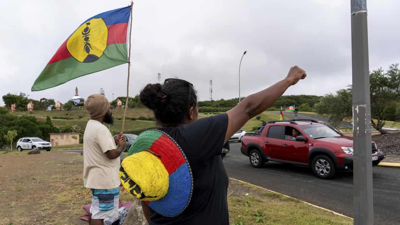 Man and woman with FLNKS flag and colours in Noumea