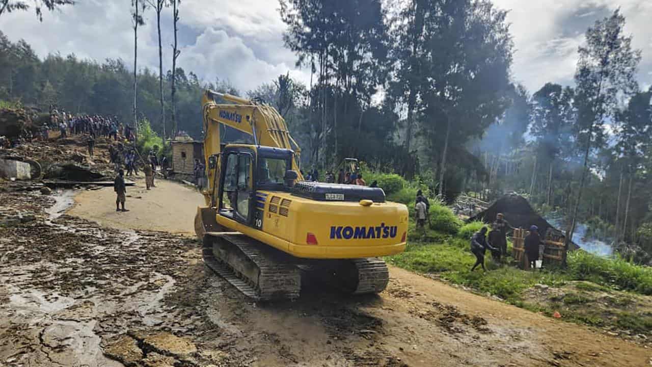 Villagers use heavy machinery to search through a landslide in Yambali