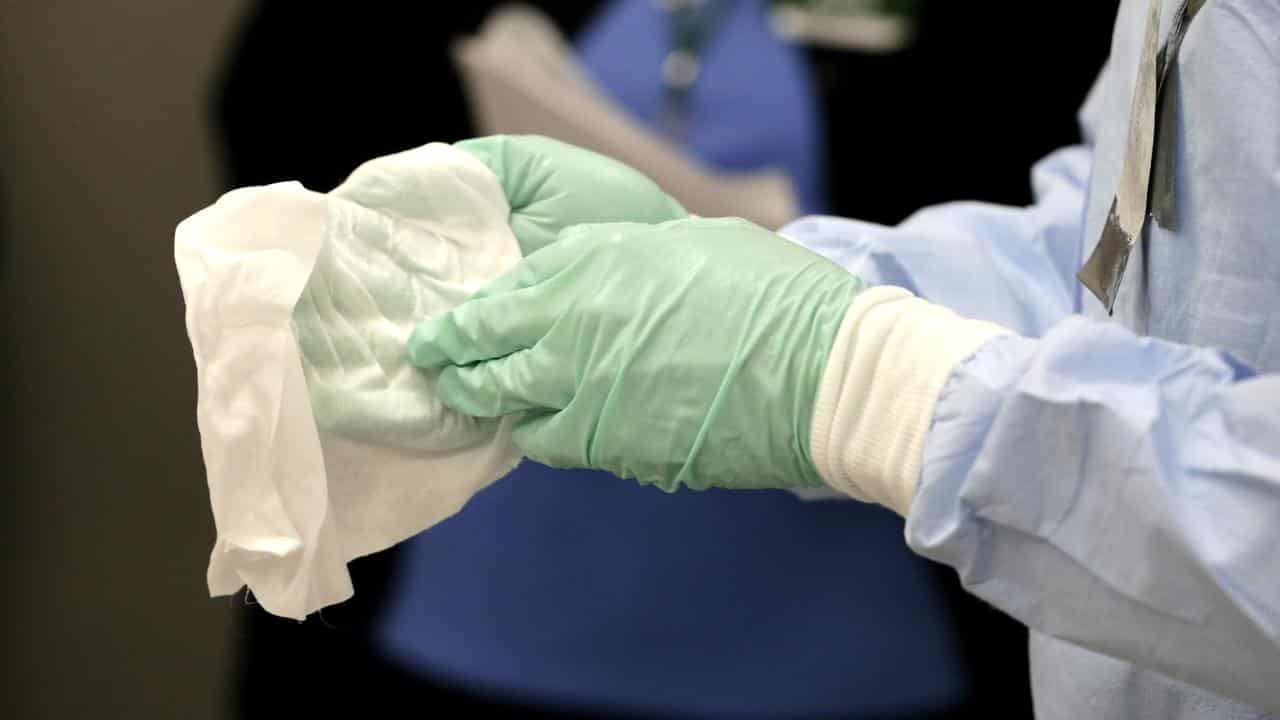 A nurse demonstrating how to clean surgical gloves using bleach.