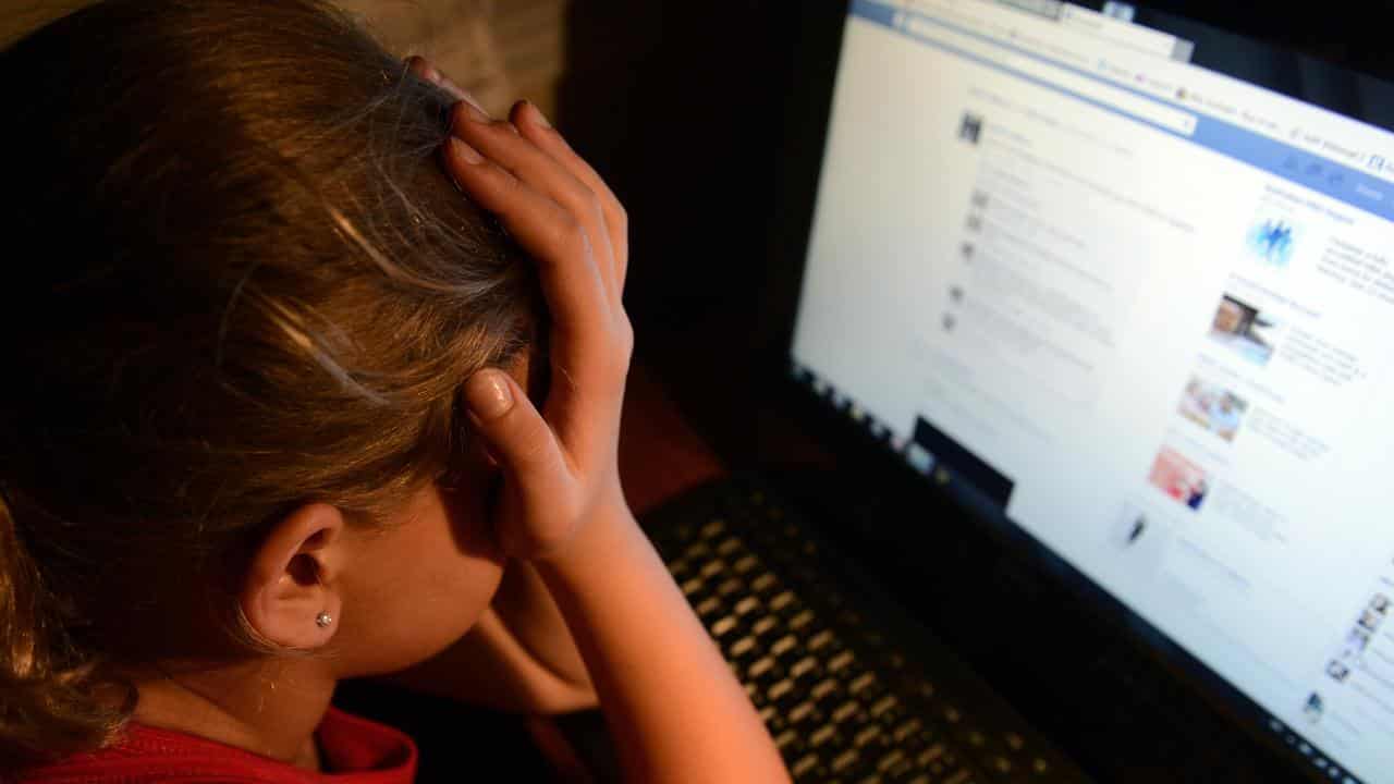 an upset young girl in front of a personal computer