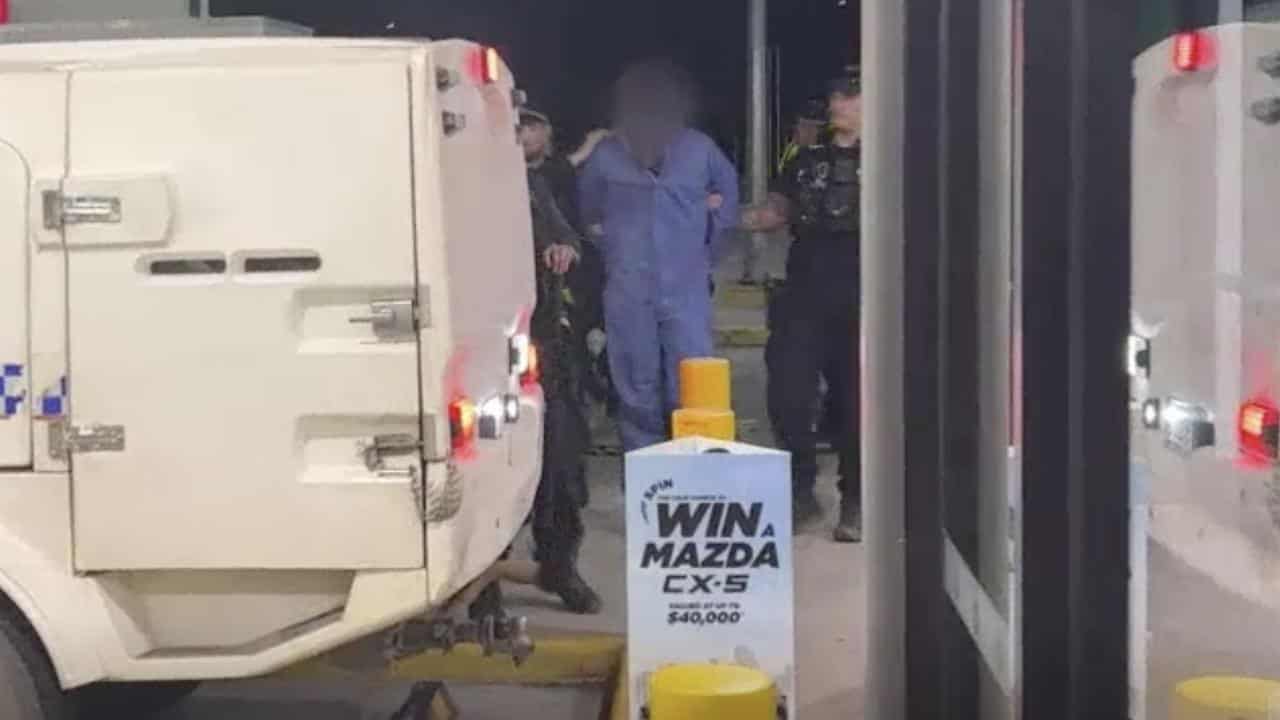 Officers lead a man to a police truck.