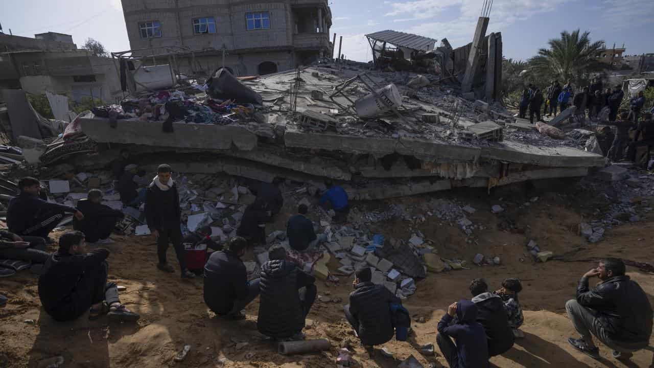 Palestinians search in the rubble of a destroyed building in Rafah