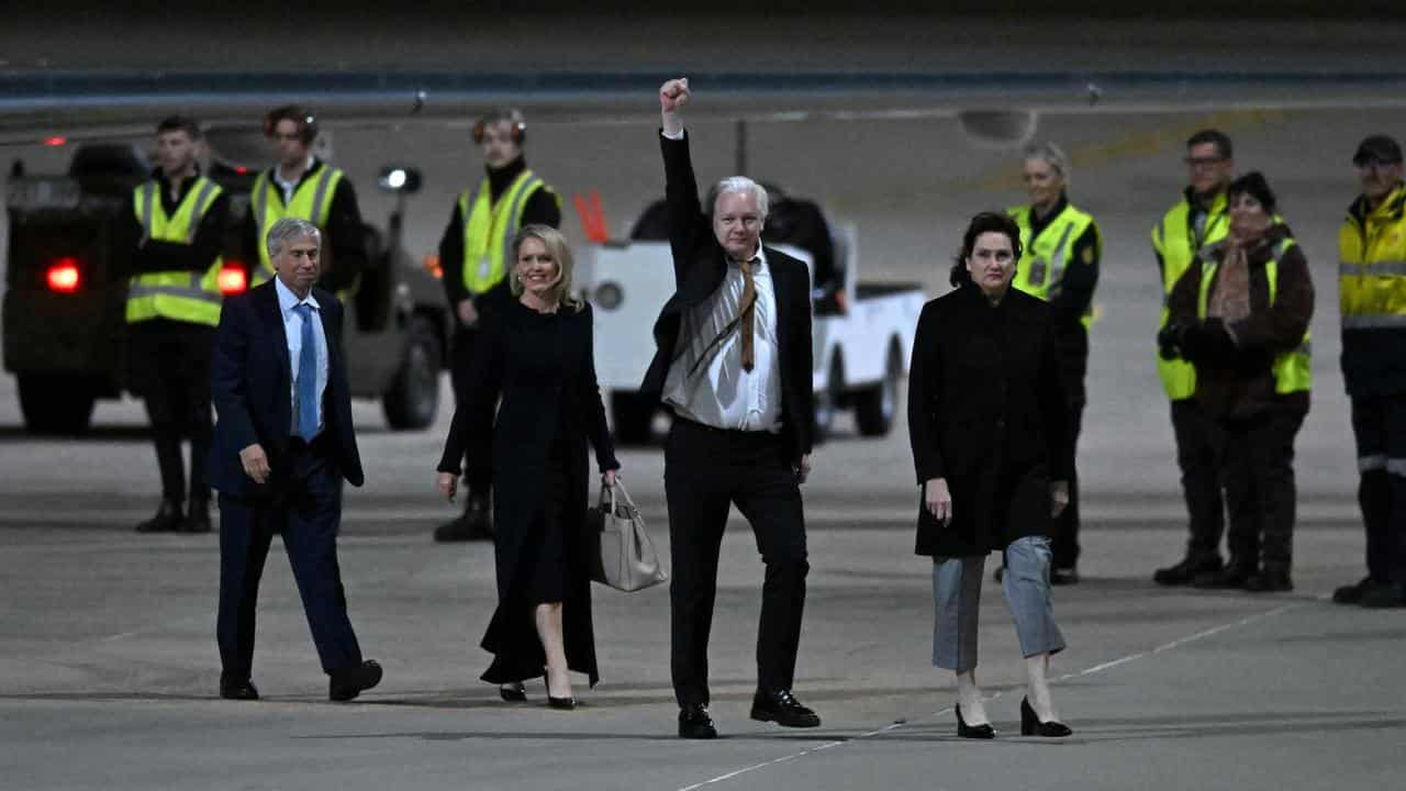 Julian Assange waves at supporters after arriving at Canberra Airport