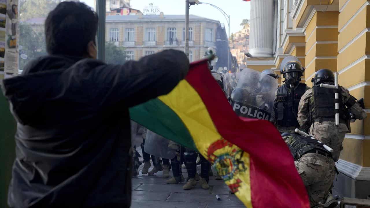 A man waves a Bolivian flag as soldiers flee from Plaza Murillo