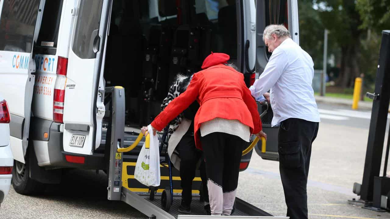 An elderly woman uses a hydraulic wheelchair platform