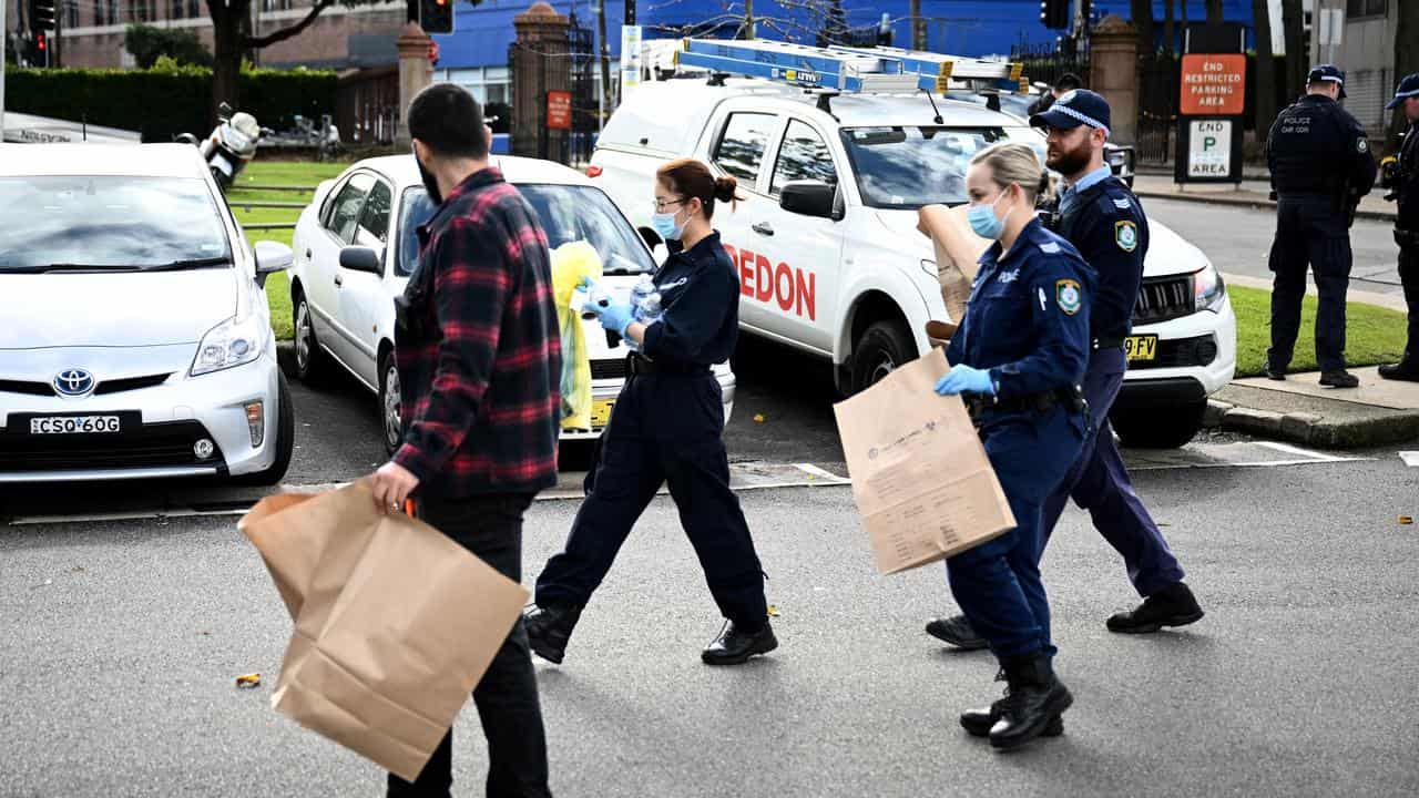 Police officers carrying evidence bags.