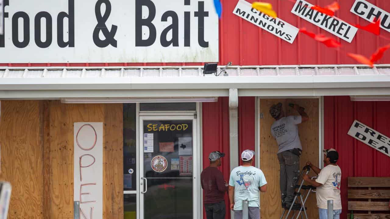 Workers board up the doorway of a business in Matagorda