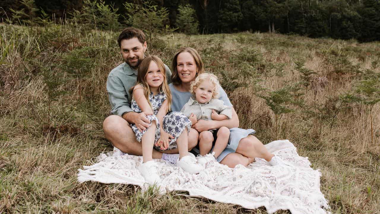 A family sit on a picnic rug.