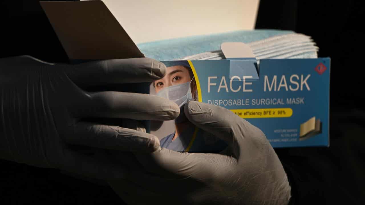 Two hands holding a box of surgical masks.