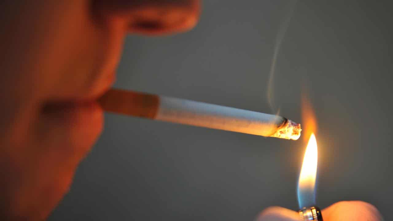 A man seen lighting a cigarette