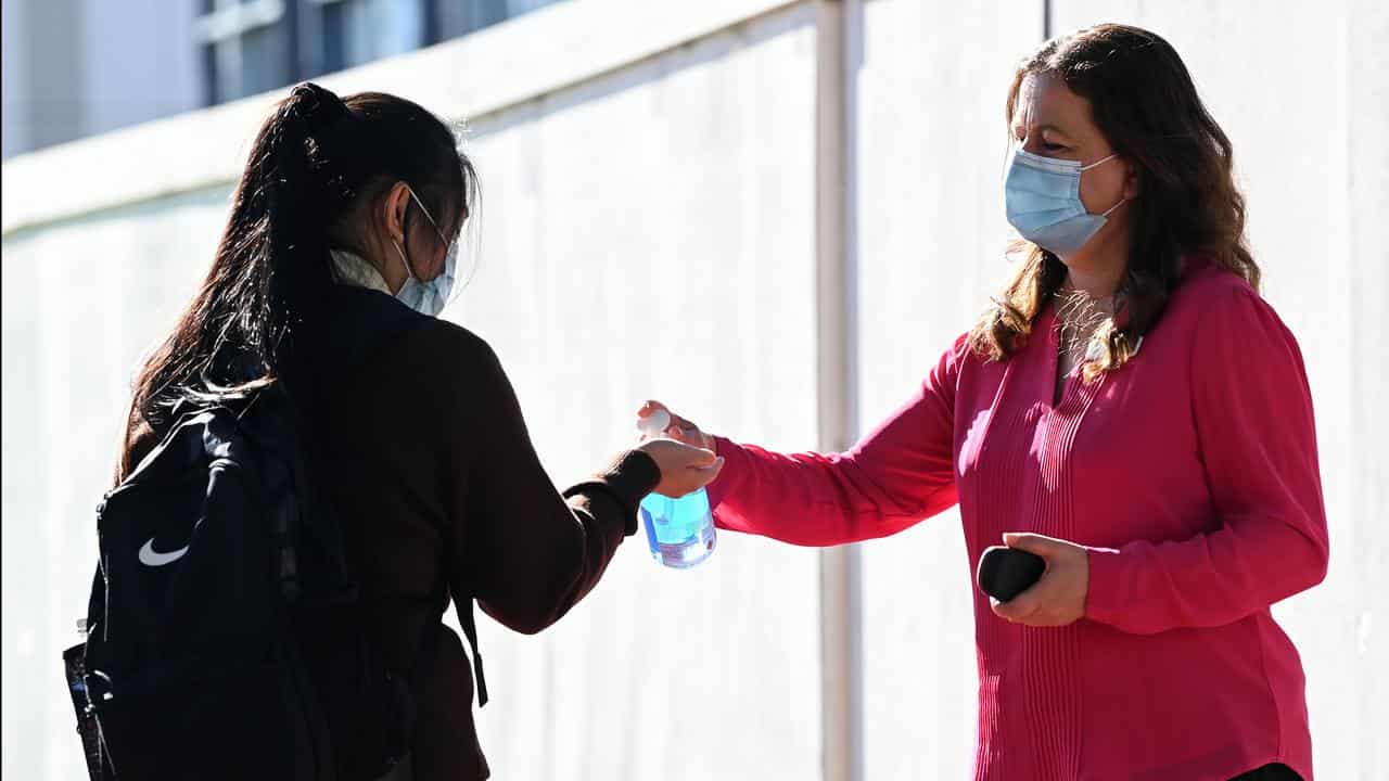 Hand sanitiser and face masks being provided to a student