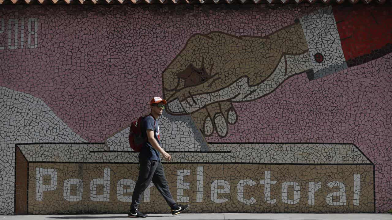 A man walks by a mural depicting a ballot box