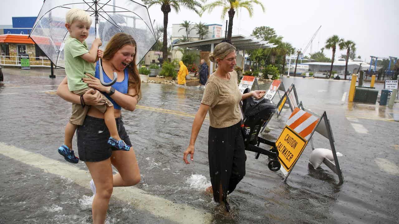 People walk through a flooded street as Hurricane Debby approaches