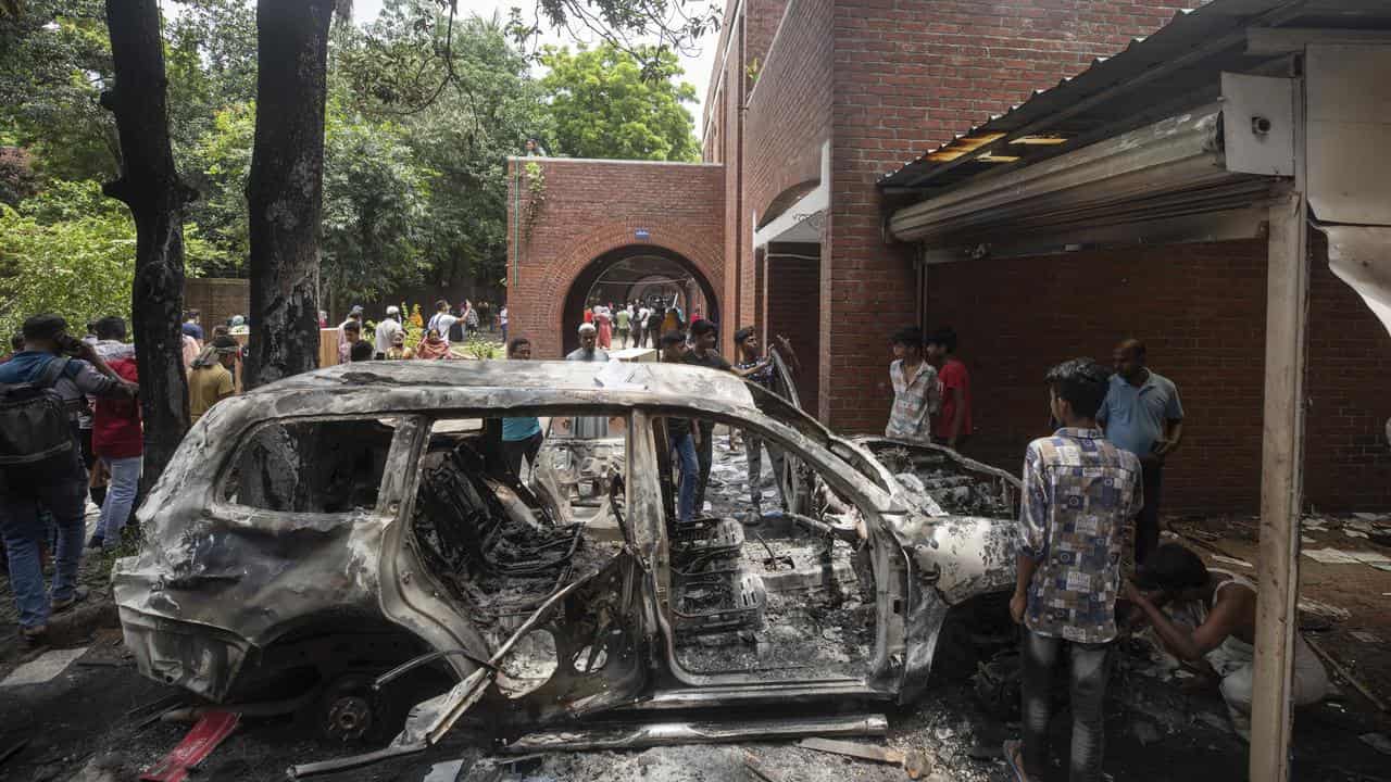 A burnt car stands in the vandalised house of Sheikh Hasina in Dhaka