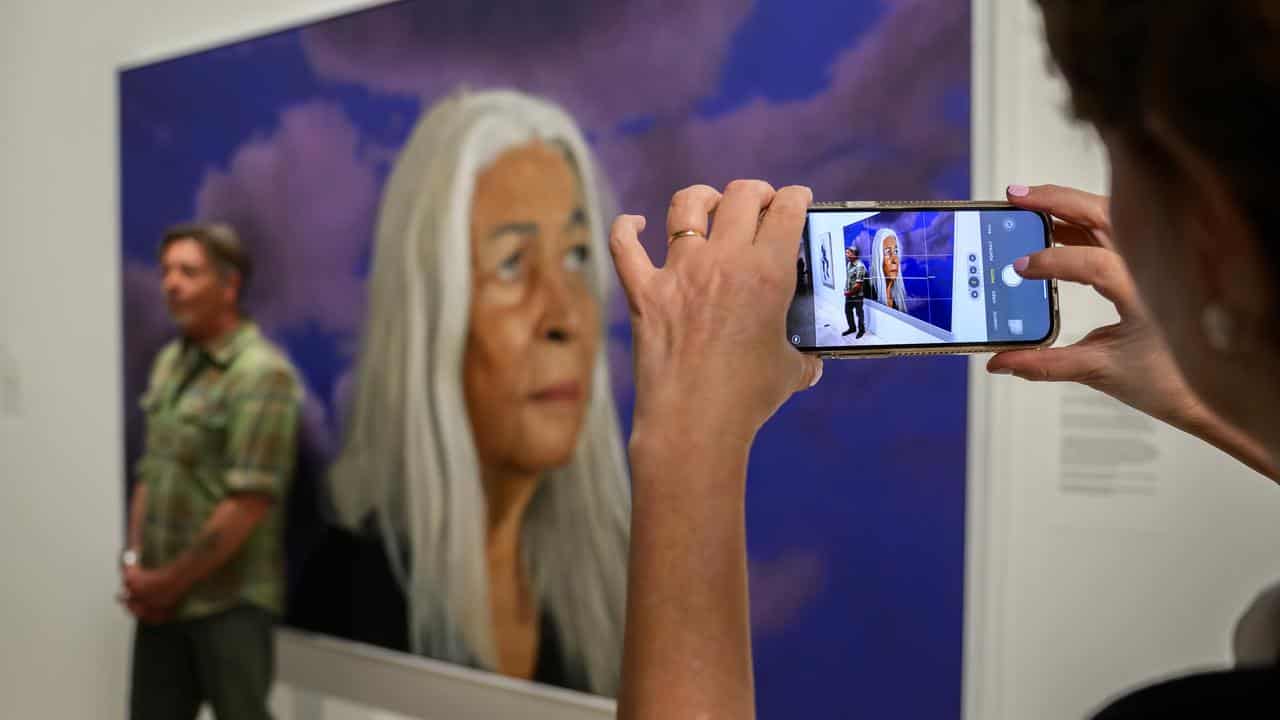 Member of the public takes a photo of Angus McDonald with his portrait