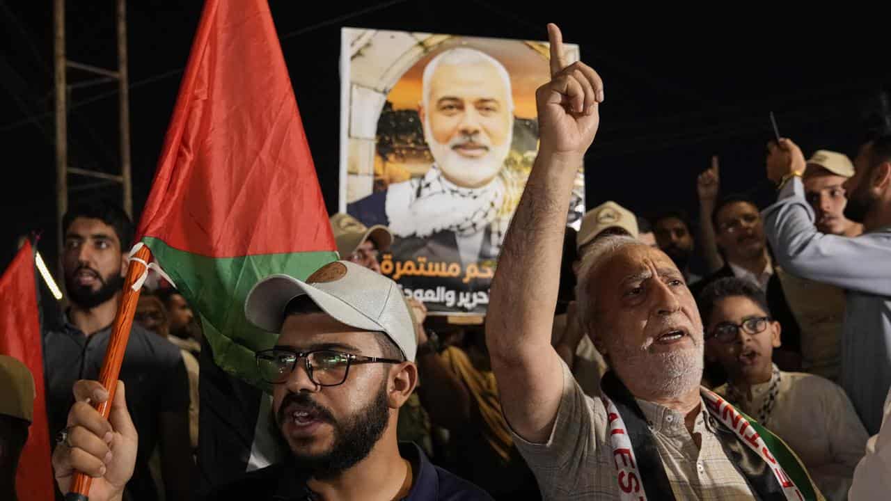 A demonstrator holds a picture of Hamas leader Ismail Haniyeh, in Iraq