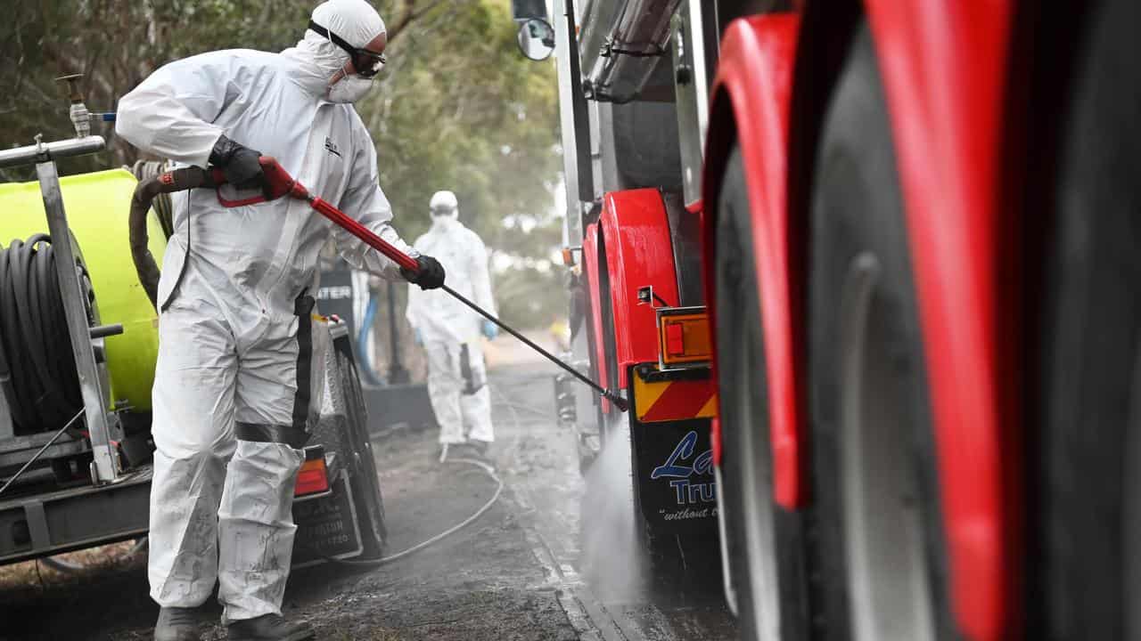 Hazmat-suited workers clean a truck in a quarantine zone in Victoria.