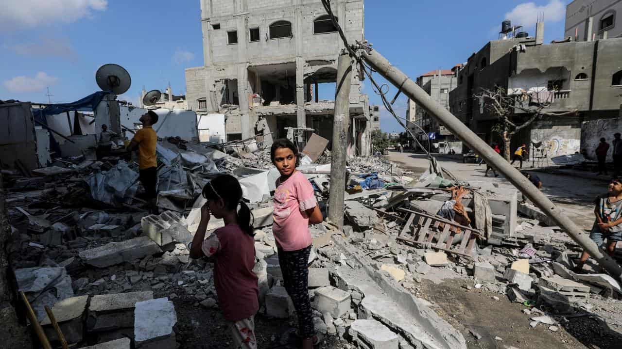 Palestinians inspect a destroyed house in Al Maghazi refugee camp