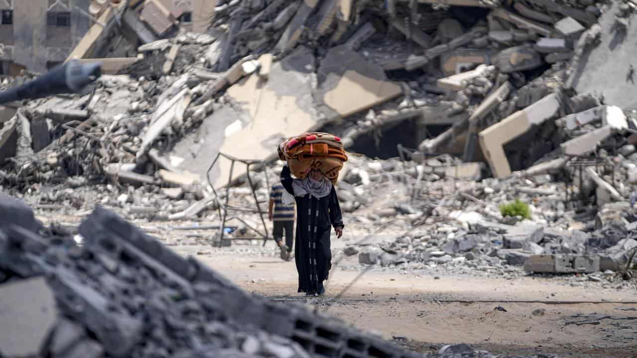 A woman walks among rubble while fleeing Hamad City, Gaza