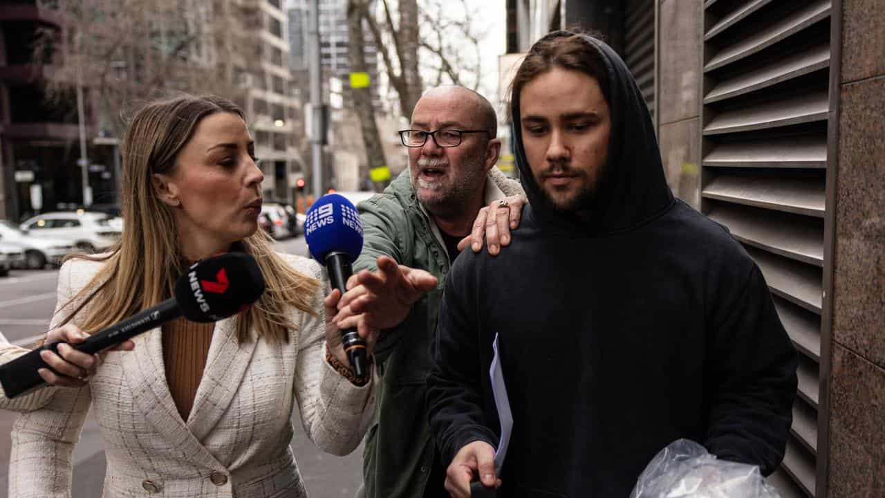 Timothy Pledger (centre) tries to stop journalists questioning his son