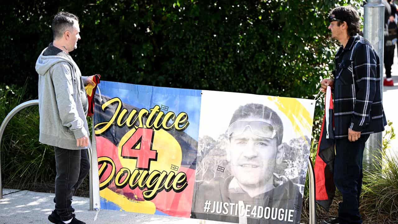 Family and friends hold banners with Rick Hampson’s image