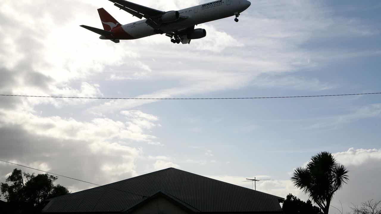 A plane flies over a house.