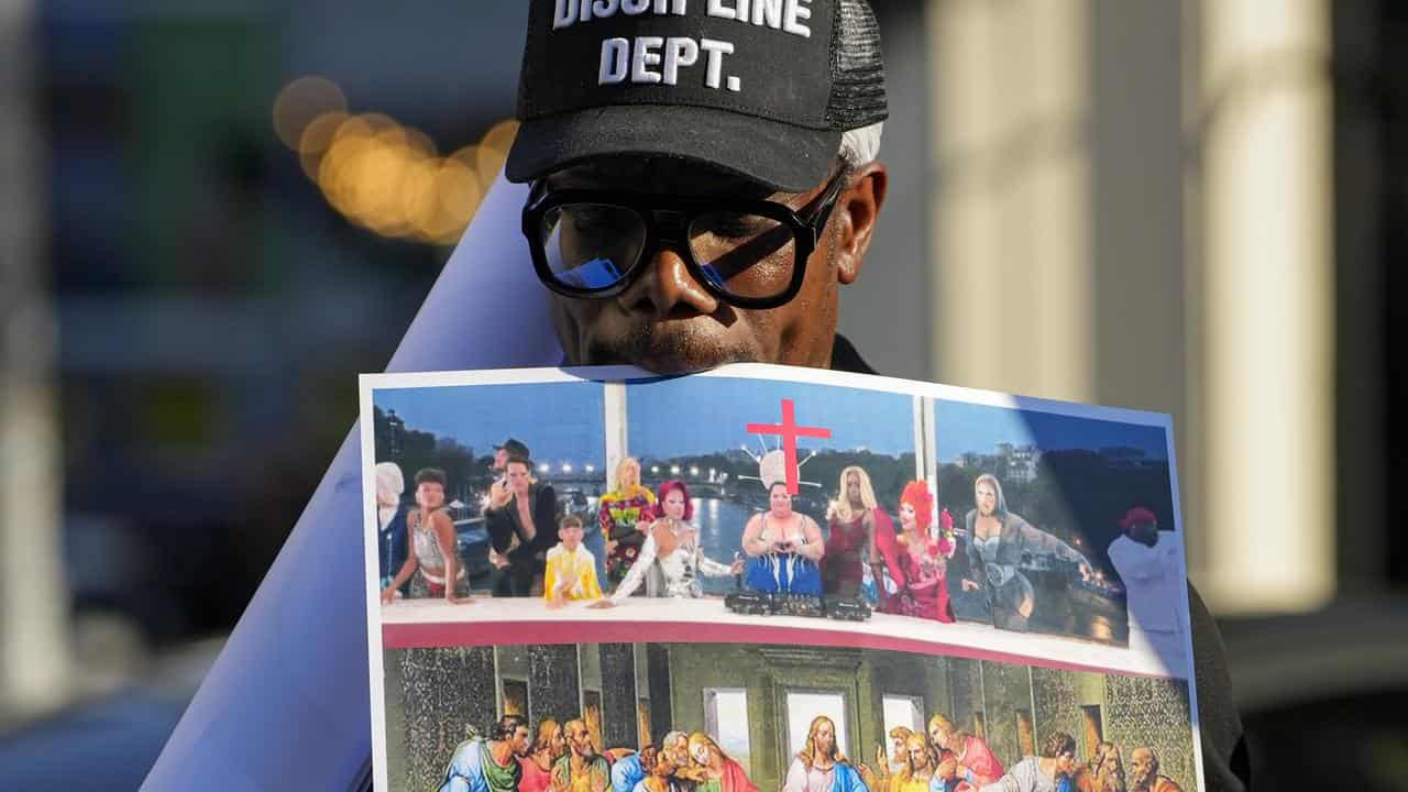 A man holds a poster at a protest over the Olympics opening ceremony 