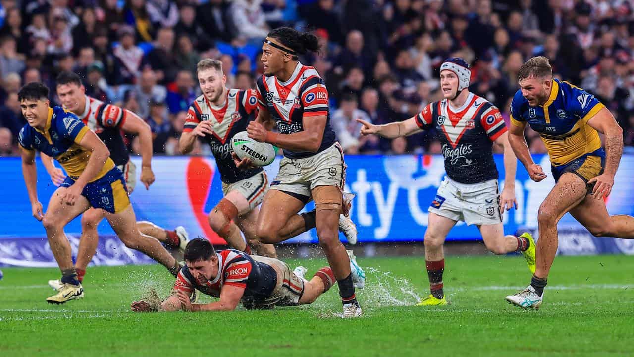 A Roosters player splashes onto the turf.