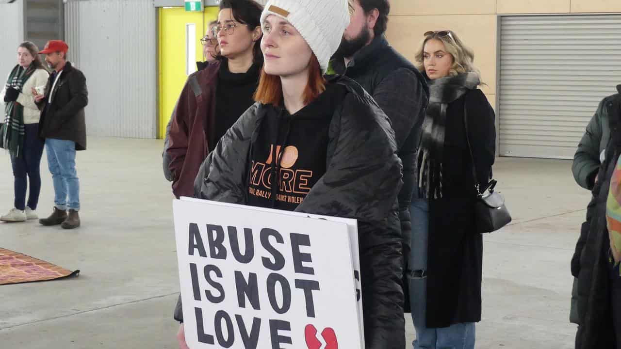 A woman holds a sign.