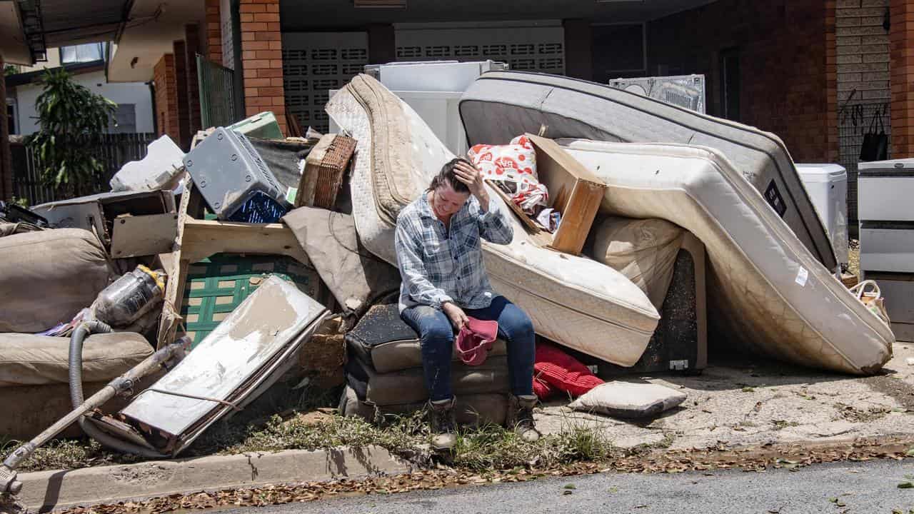 A woman sits on flood-damaged furniture.