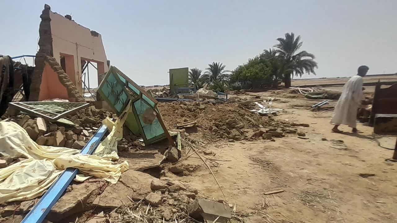 A man walks next to his home damaged floods in Meroe