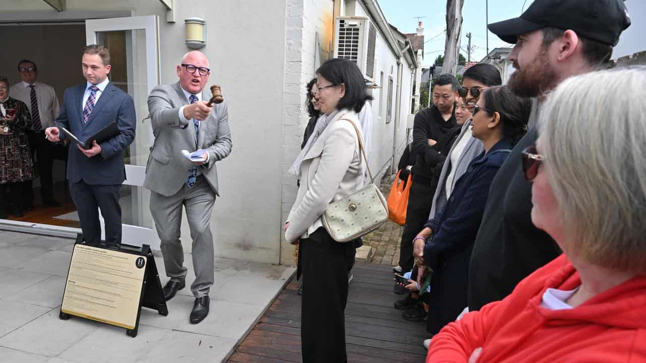 An auctioneer congratulates the winning buyers of a house