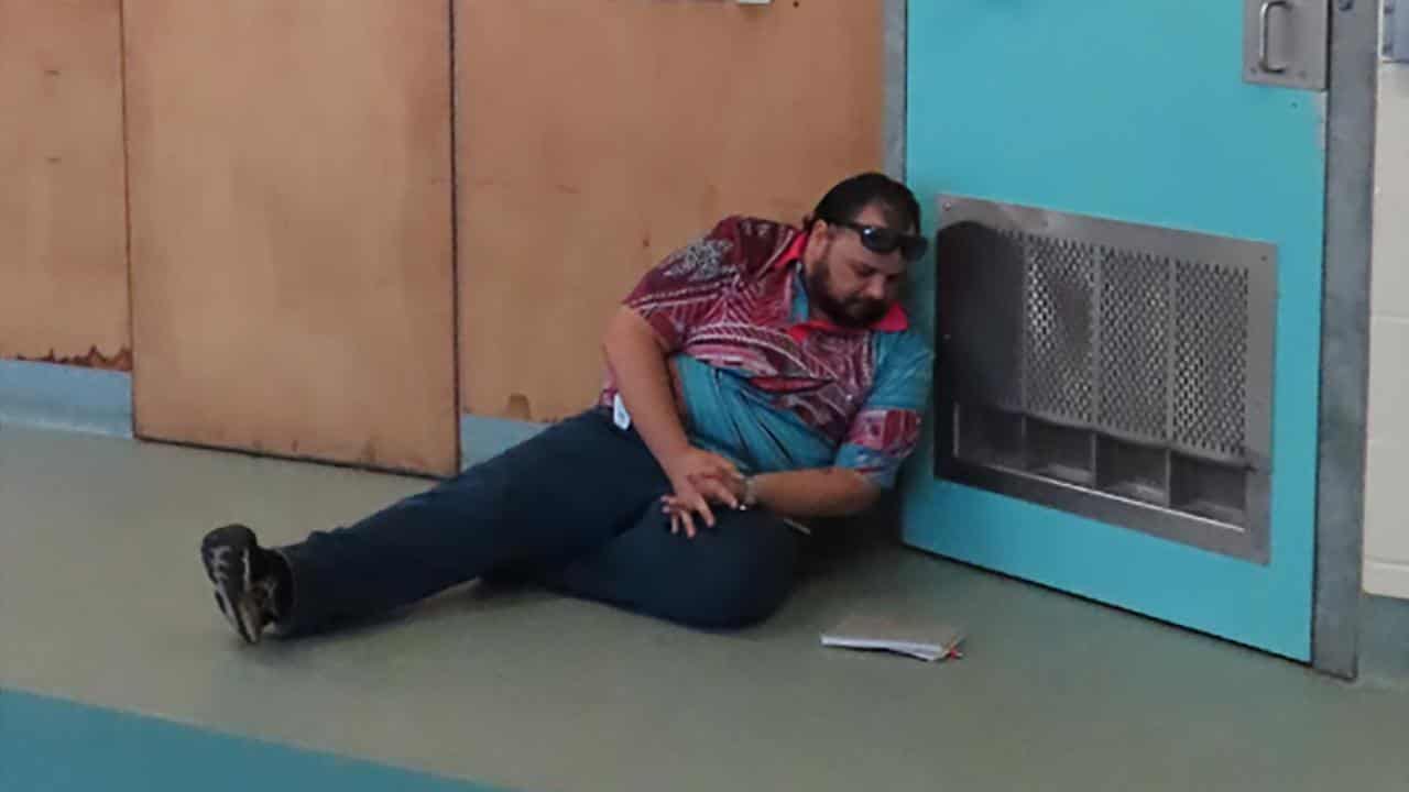 A man sits on a floor outside a door.