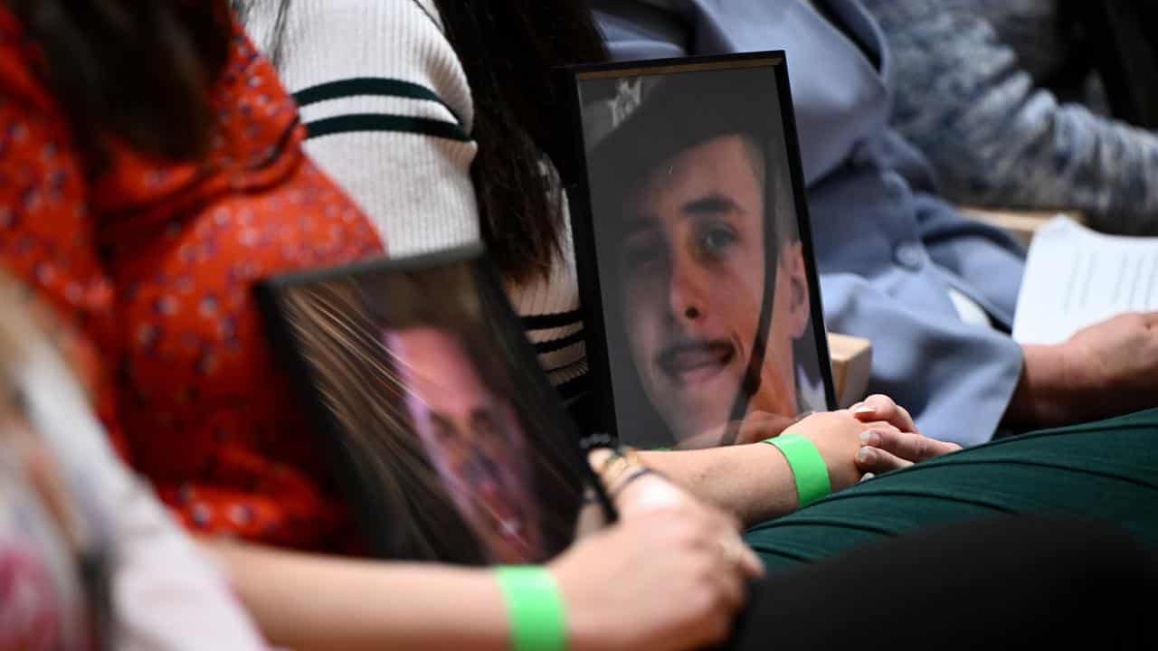 Attendees hold portraits of ADF family and friends