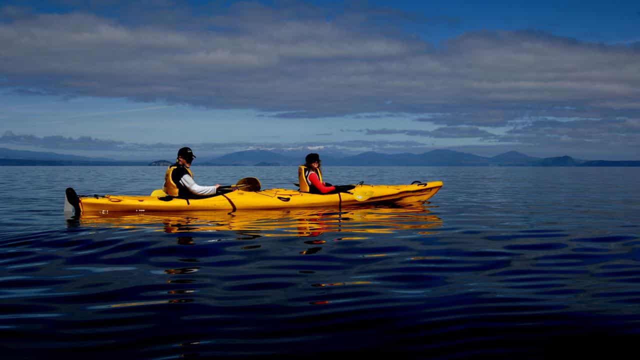 Visitors kayak on Lake Taupo in the North Island of New Zealand.