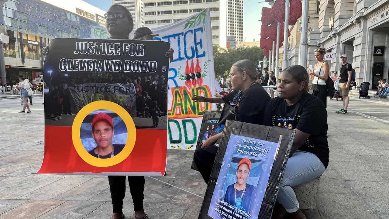 Protesters hold signs.