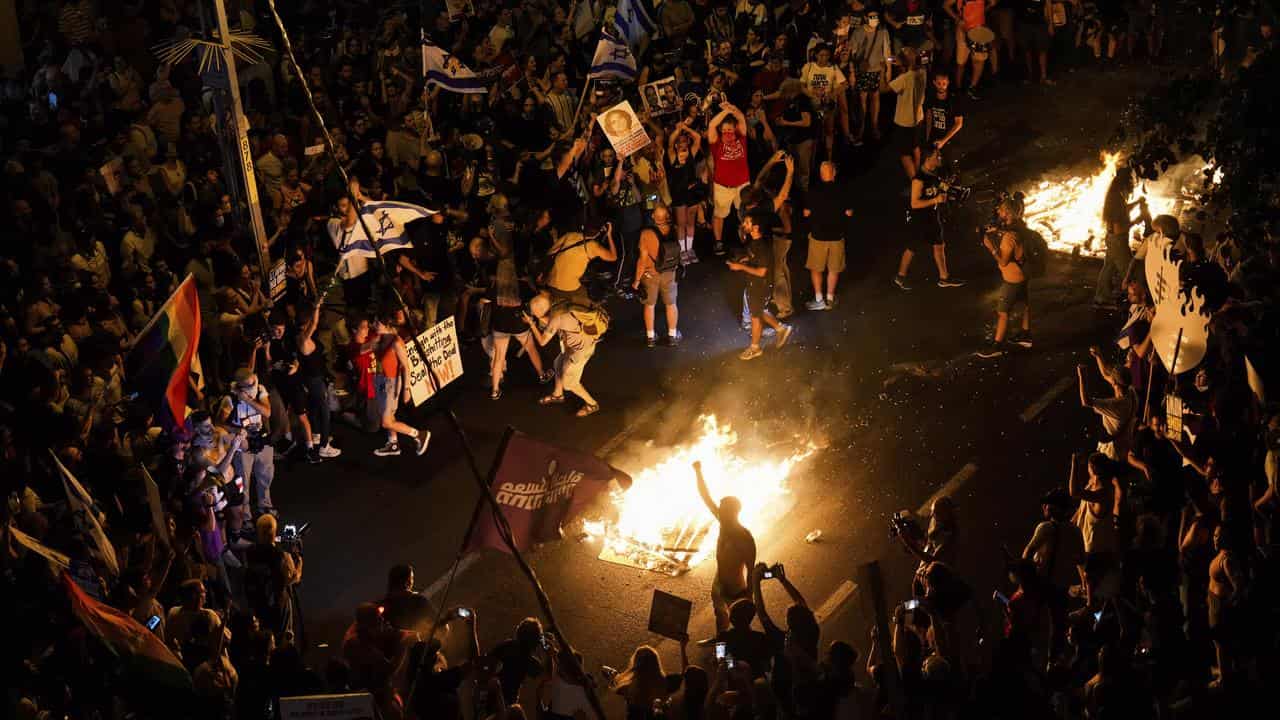 Protesters light a bonfire during a protest demanding a cease-fire 