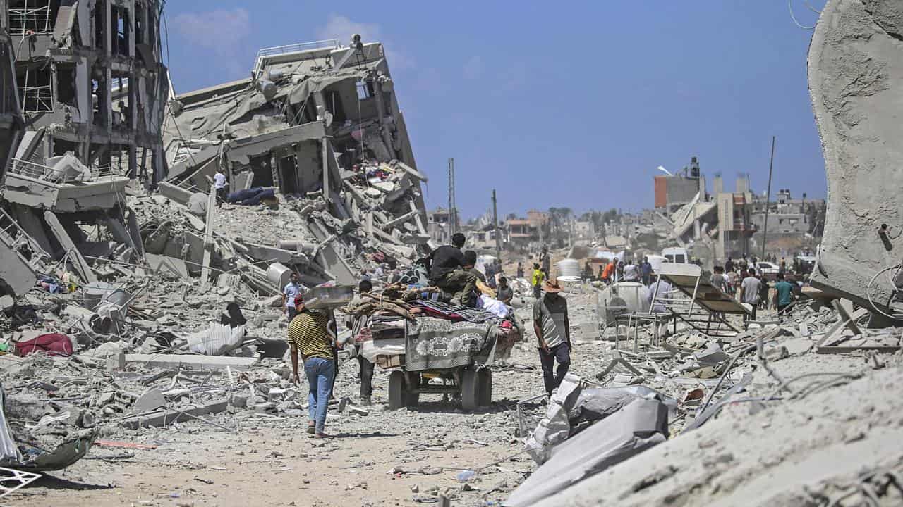 People stand among the rubble of buildings.