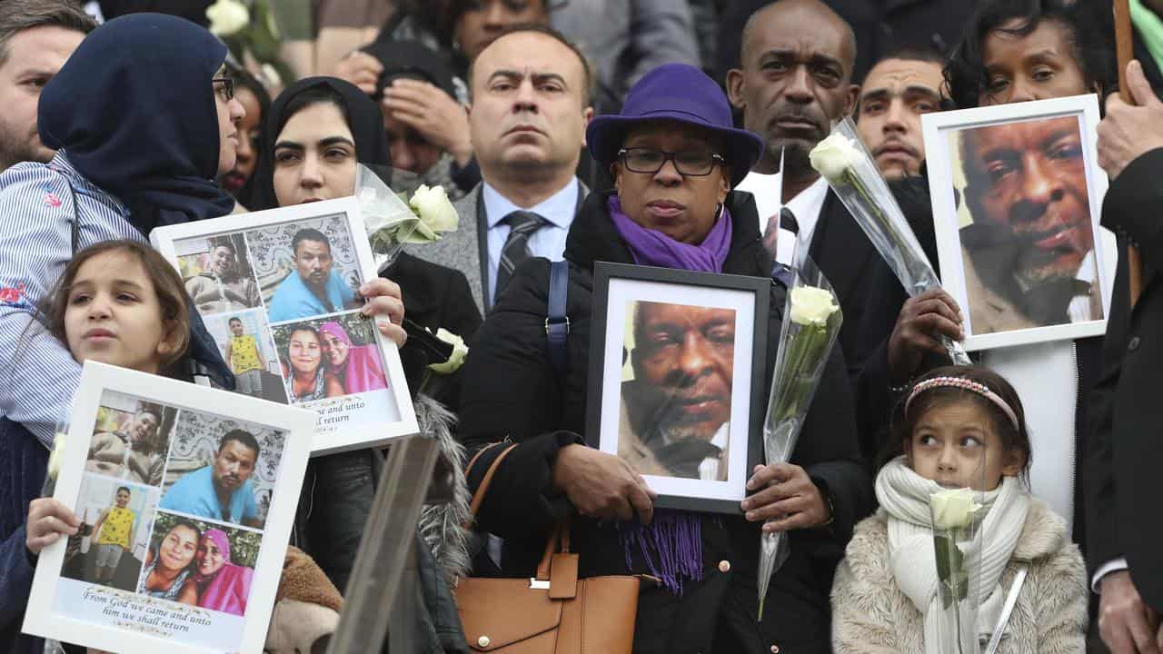 People hold up photos of victims of the Grenfell Tower fire in 2017